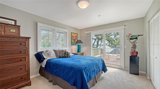 bedroom with multiple windows, light carpet, and access to outside