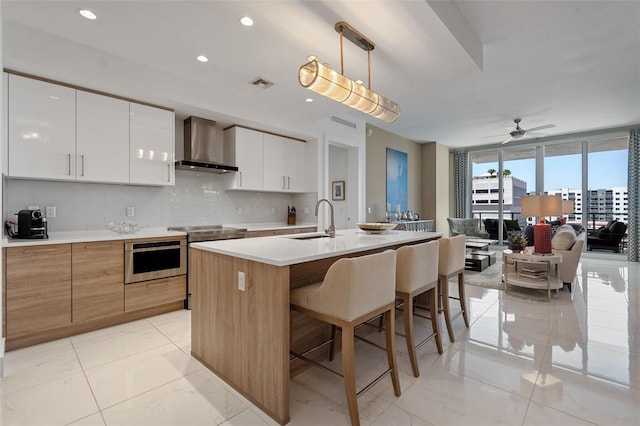 111 S Pineapple Ave Unit 716, Sarasota, FL 34236 - kitchen featuring a sink, stainless steel oven, wall chimney exhaust hood, backsplash, and visible vents
