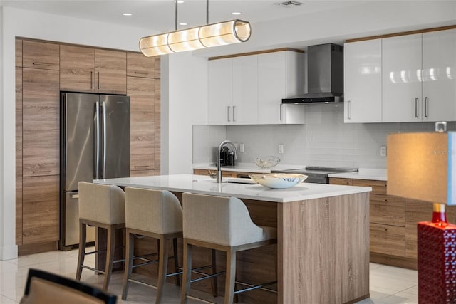 111 S Pineapple Ave Unit 716, Sarasota, FL 34236 - kitchen with wall chimney range hood, light countertops, a sink, freestanding refrigerator, and a breakfast bar