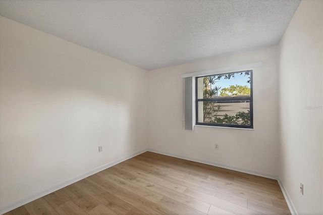 752 White Pine Tree Rd Unit 101, Venice, FL 34285 - empty room with a textured ceiling, light wood finished floors, and baseboards