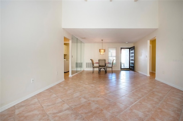 3843 El Poinier Ct W Unit 8720, Sarasota, FL 34232 - unfurnished room with a chandelier, a high ceiling, washer / clothes dryer, baseboards, and light tile patterned flooring