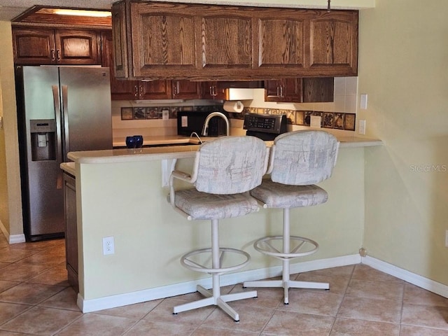 3843 El Poinier Ct W Unit 8720, Sarasota, FL 34232 - kitchen with stainless steel fridge, baseboards, light tile patterned flooring, and light countertops