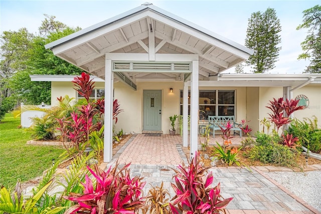 property entrance featuring covered porch and stucco siding