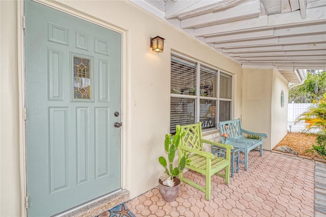 doorway to property with a porch and stucco siding