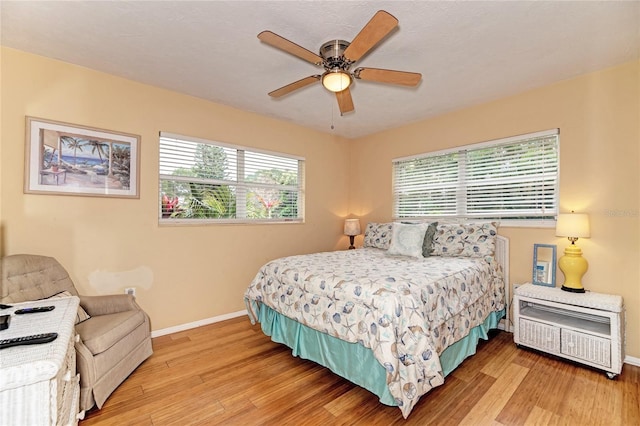 bedroom with baseboards, light wood-type flooring, and a ceiling fan