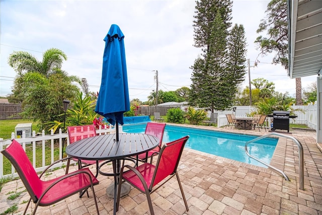 view of swimming pool with a patio, a fenced in pool, a fenced backyard, area for grilling, and outdoor dining space