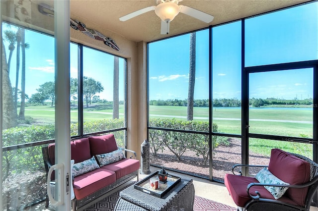sunroom featuring golf course view, a ceiling fan, a water view, and an outdoor hangout area