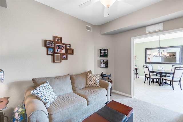 living room with a chandelier, a ceiling fan, light carpet, baseboards, and light tile patterned floors