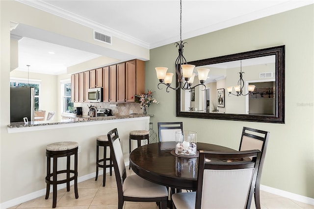 dining area with a chandelier, ornamental molding, baseboards, and light tile patterned floors
