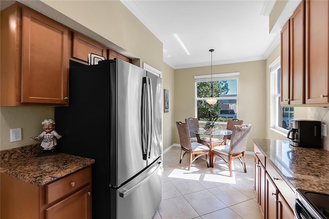 kitchen featuring crown molding, stainless steel appliances, light tile patterned floors, brown cabinets, and dark stone countertops