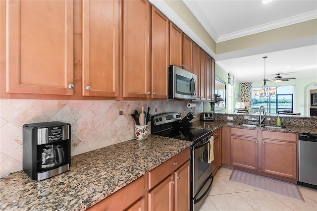 kitchen featuring stainless steel appliances, a sink, brown cabinets, ornamental molding, and dark stone counters