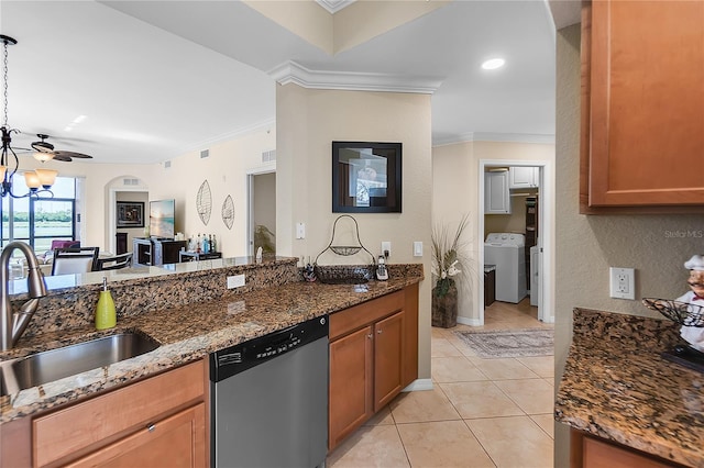 kitchen featuring stainless steel dishwasher, washer / clothes dryer, ornamental molding, a sink, and dark stone countertops