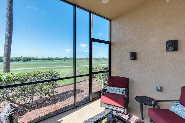 sunroom / solarium featuring view of golf course and a water view