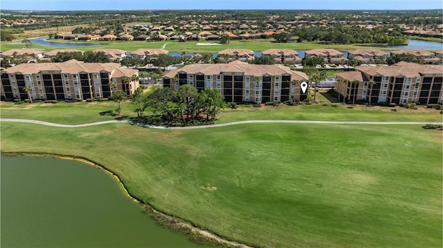 drone / aerial view of apartment complex, a golf course, and a large body of water