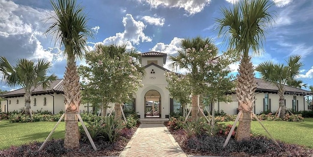 mediterranean / spanish-style home with stucco siding, a tile roof, and a front yard