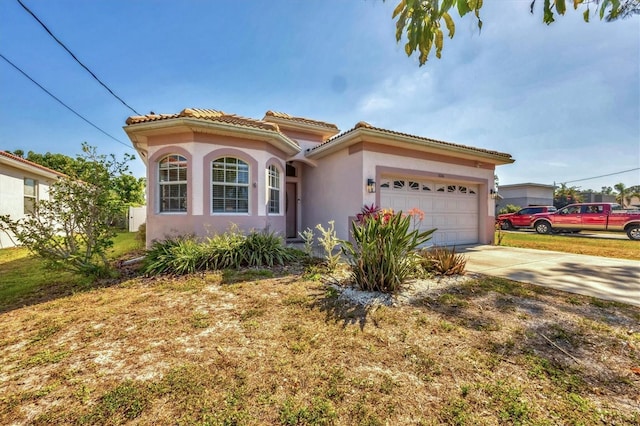 mediterranean / spanish house featuring a garage, stucco siding, a tile roof, and concrete driveway