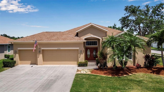 mediterranean / spanish house featuring a front yard, driveway, a garage, and stucco siding