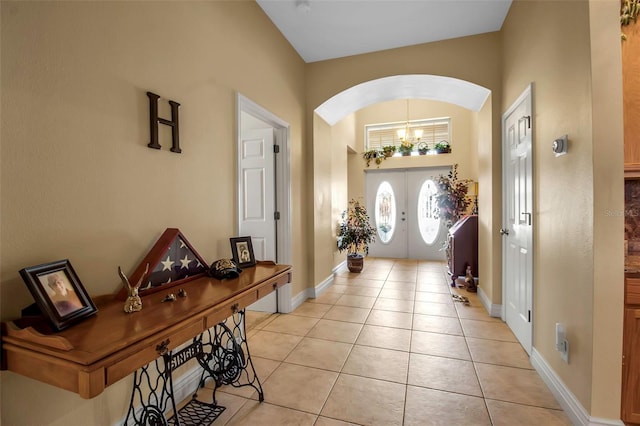 entryway featuring light tile patterned floors, french doors, baseboards, and arched walkways