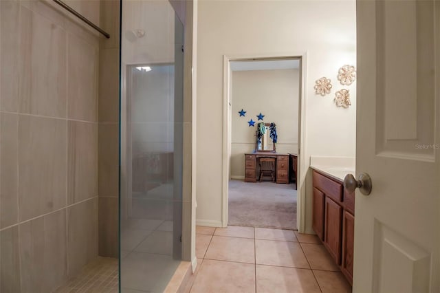 bathroom with a tile shower, tile patterned flooring, and vanity