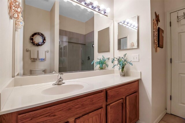 bathroom featuring tile patterned floors, vanity, toilet, and a stall shower