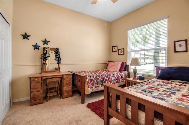bedroom with a ceiling fan, a closet, light colored carpet, and baseboards