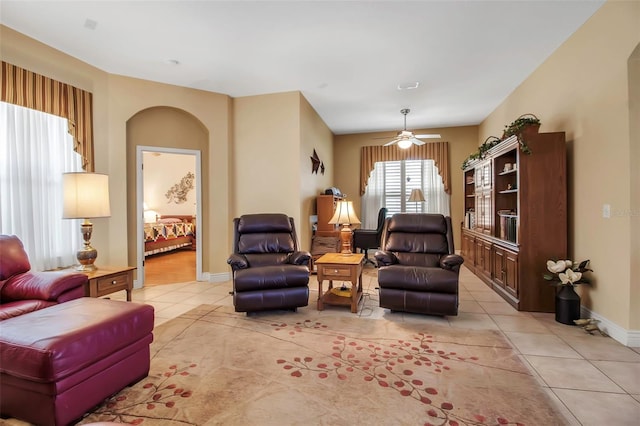 living room featuring baseboards, light tile patterned floors, and ceiling fan
