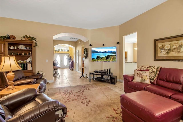 living area featuring baseboards, light tile patterned floors, arched walkways, and visible vents