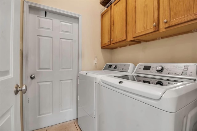 laundry area featuring light tile patterned floors, washing machine and clothes dryer, and cabinet space