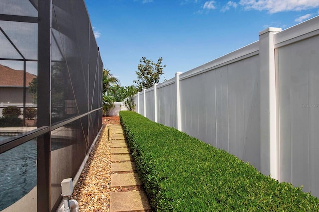 view of yard featuring fence and glass enclosure