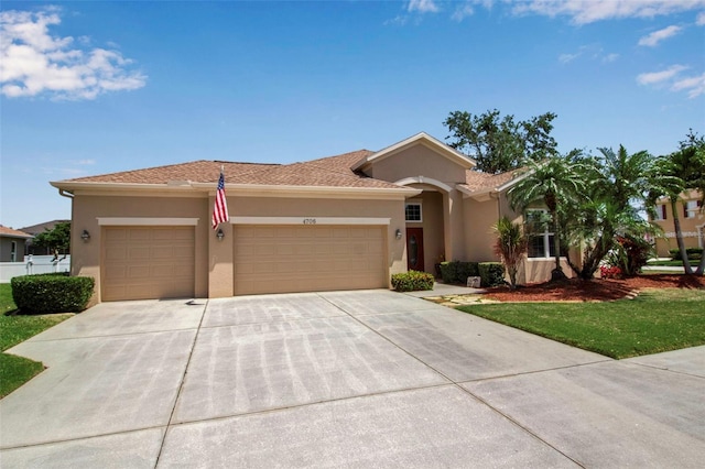 view of front of property featuring stucco siding, a front lawn, concrete driveway, and an attached garage