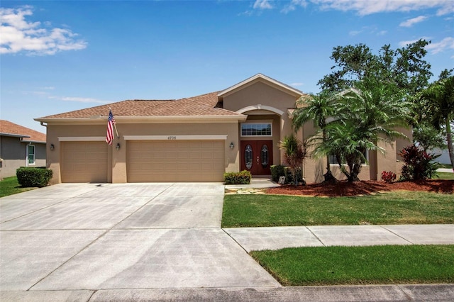 mediterranean / spanish-style home featuring stucco siding, driveway, a front lawn, and a garage