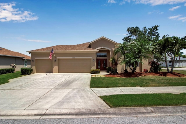 mediterranean / spanish-style house with an attached garage, a front yard, driveway, and stucco siding