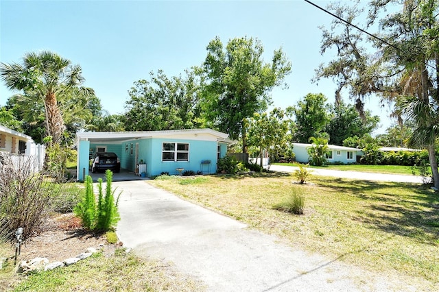 view of front of home featuring fence, an attached carport, a front yard, and aphalt driveway