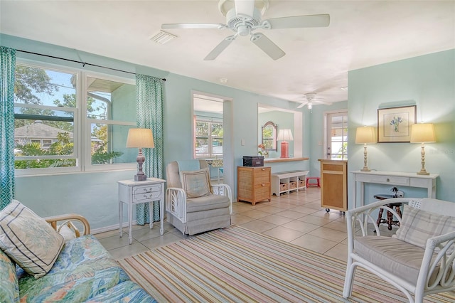 living room featuring baseboards, ceiling fan, visible vents, and light tile patterned floors