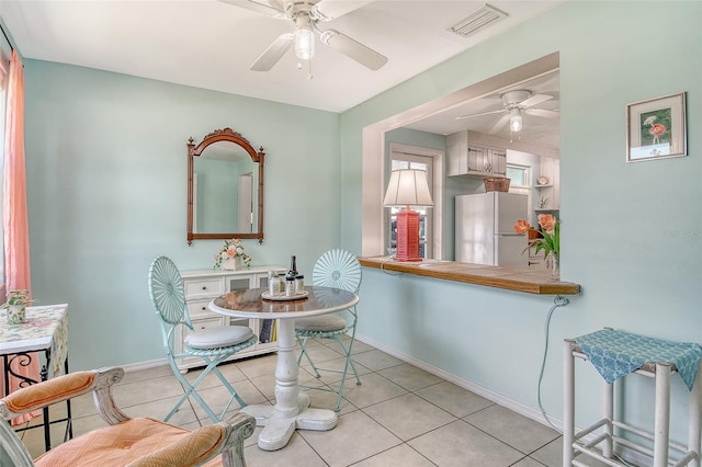 dining area with light tile patterned floors, baseboards, ceiling fan, and visible vents