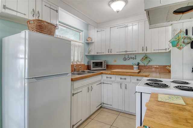 kitchen featuring white appliances, white cabinets, ventilation hood, and a sink