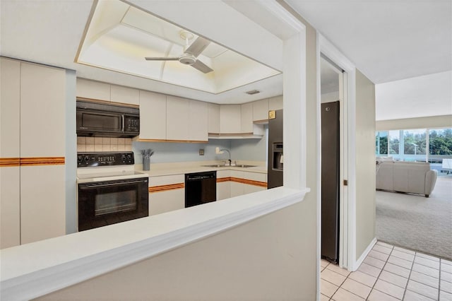 kitchen with light tile patterned floors, a sink, light colored carpet, light countertops, and black appliances