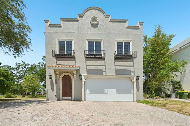 view of front of home with stucco siding, a balcony, decorative driveway, and a garage
