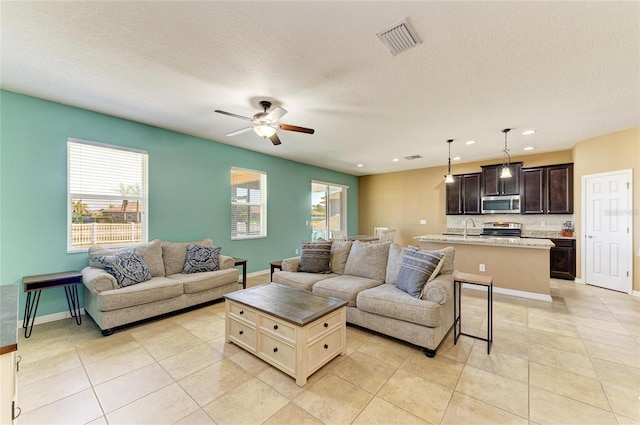 7822 110th Ave E, Parrish, FL 34219 - living area with visible vents, a ceiling fan, a textured ceiling, and light tile patterned flooring