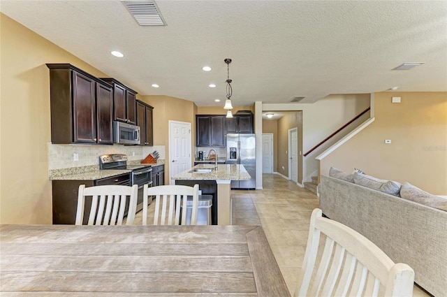 7822 110th Ave E, Parrish, FL 34219 - kitchen with a sink, appliances with stainless steel finishes, visible vents, dark brown cabinets, and open floor plan