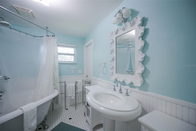 full bathroom with visible vents, tile patterned flooring, wainscoting, curtained shower, and a bathing tub