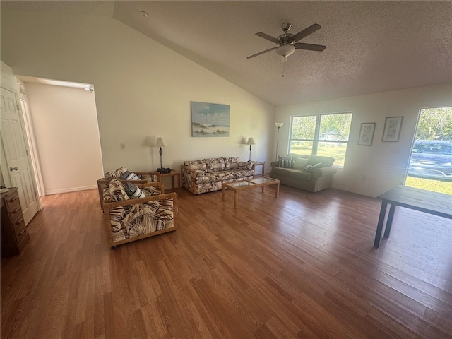 living room with a textured ceiling, ceiling fan, vaulted ceiling, and wood finished floors