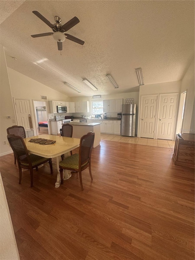 dining area featuring a textured ceiling, light wood-style floors, and ceiling fan