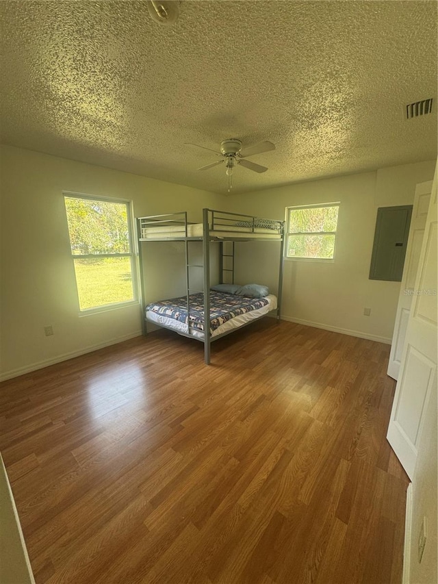 unfurnished bedroom featuring a textured ceiling, visible vents, wood finished floors, and baseboards