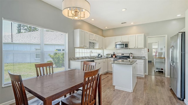 12339 Hollybush Ter, Lakewood Ranch, FL 34202 - kitchen with appliances with stainless steel finishes, a sink, a kitchen island, white cabinets, and recessed lighting