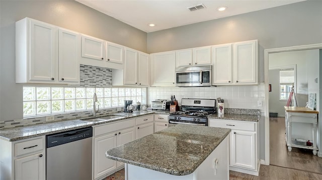 12339 Hollybush Ter, Lakewood Ranch, FL 34202 - kitchen featuring stainless steel appliances, a sink, white cabinets, backsplash, and dark stone counters