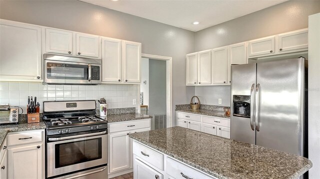 12339 Hollybush Ter, Lakewood Ranch, FL 34202 - kitchen featuring stainless steel appliances, decorative backsplash, white cabinetry, dark stone counters, and recessed lighting