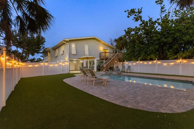 view of pool featuring a wooden deck, stairway, a fenced backyard, a patio, and a yard