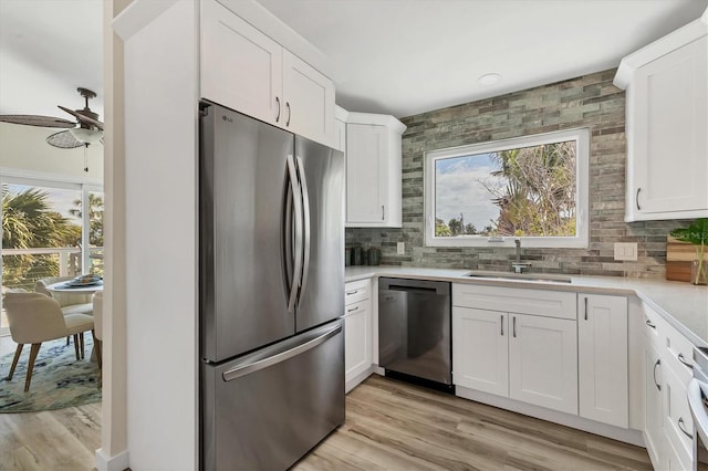 kitchen with backsplash, white cabinetry, appliances with stainless steel finishes, and a sink