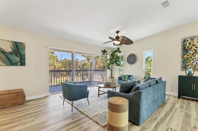 living room with a ceiling fan, visible vents, plenty of natural light, and wood finished floors